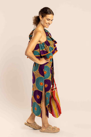 A sophisticated and feminine dress that screams 'Africa'! 100% made in South Africa from pure cotton, this Midi long dress features a rather tight fit at the waist that flares out over the skirt, thanks to a matching wrap around belt. It has side splits and ric-rac trim. What makes it unique are the tribal pattern it features and the off shoulder detail, the two frills make it extremely playful and perfect for your everyday life. 