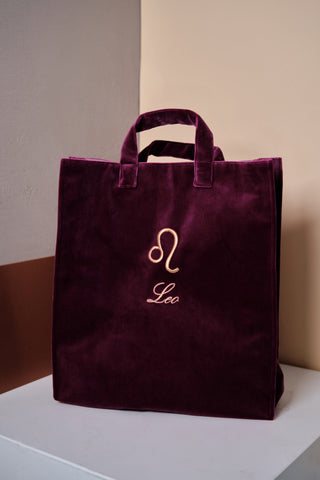 Inspired by the illuminating art of astrology, Nina Leuca's velvet tote bag is a daily celebration of the colourful, cheerful, and creative Leo woman. The ﻿fuchsia zodiac bag features a gold zodiac symbol and a delicately emboroidered astrology sign pattern on a soft, velvet base